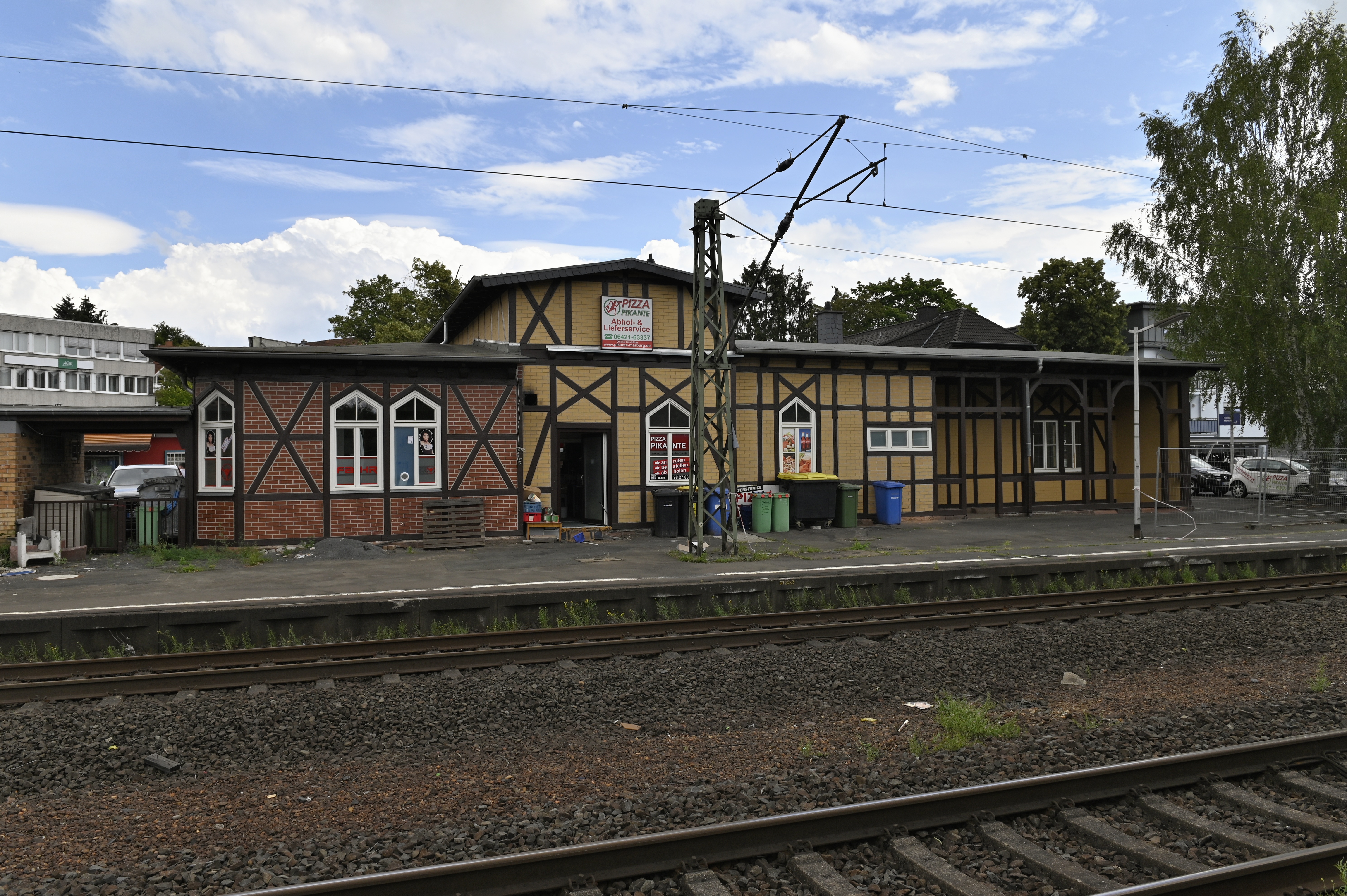 Foto der Haltestelle Marburg Süd, mit Bahnhofsgebäude und Schienen in nicht-barrierefreiem Zustand